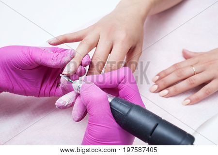 Hardware manicure. Removal of old gel varnish in the salon. Manicure master doing beauty procedure for client, closeup and top view