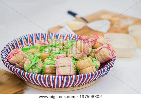 Wicker plate with the colors of the national flag with traditional organic small heads of french cheese, tied together, few pieces in the market. Gastronomic products for gourme