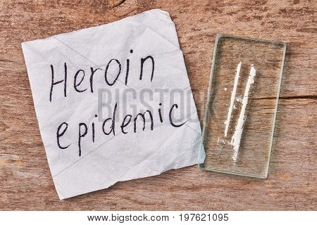 Concept of drugs global addiction. Text heroin epidemic, narcotics, wooden background.