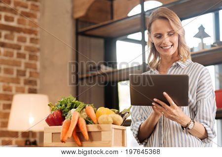 Online search. Motivated savvy active lady using her gadget for making purchase and looking for cooking instructions while taking care of her diet