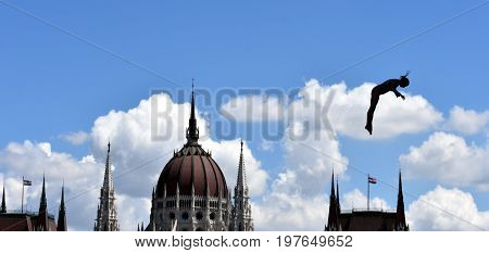 Budapest Hungary - Jul 28 2017. Woman dives from the 20 metre platform during the semi-final day of women`s High Diving at the FINA World Championships. The Hungarian Parliament in the background.
