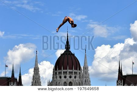 Budapest Hungary - Jul 28 2017. Man dives from the 27 metre platform during the semi-final day of men`s High Diving at the FINA World Championships. The Hungarian Parliament in the background.