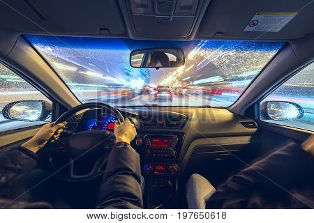 Two man in a car moves at fast speed at the winter night. Blured road with lights with car on high speed.