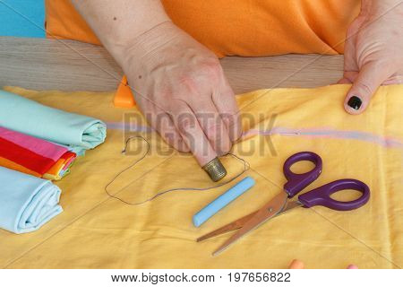 needlework and hand quilting in the workshop of a tailor woman - on the desktop of thread scissors. female in costume sewing