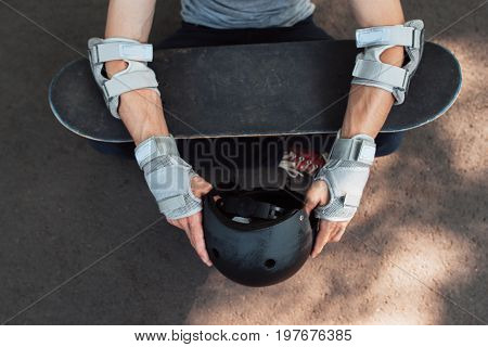 Skateboard halmet, elbow and gloves protection on unrecognizable skateboarder. Head and hands care. Extreme sport injoury. Headwear stuff for skater