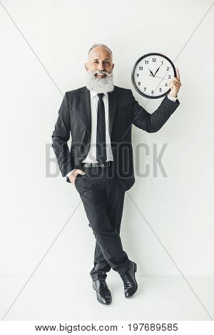 Smiling Mature Businessman Holding Clock On Ligth Background