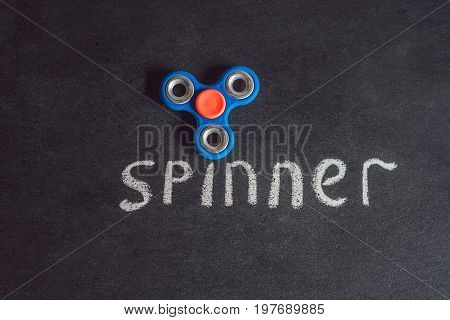 Famous Fidget Spinner Stress Relieving N A Black Wooden Background. And The Inscription Spinner