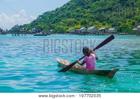 Semporna,Sabah,Malaysia-Apr 23,2017:Sea Gypsy kid girl rowing an unique handmade boat surrounded by beautiful clear water of the Bodgaya island,Semporna,Sabah,Malaysia.