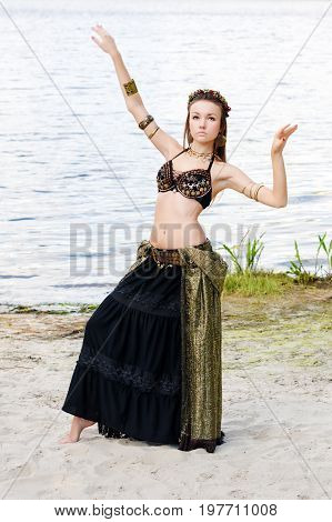 Young woman tribal american style dancer. Girl dancing and posing on the beach sand wearing belly dance costume. Ethnic dance. Belly dancing. Tribal dancing