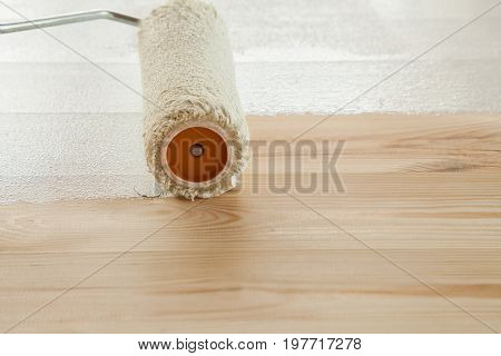 Roller paints white paint a fresh wooden floor