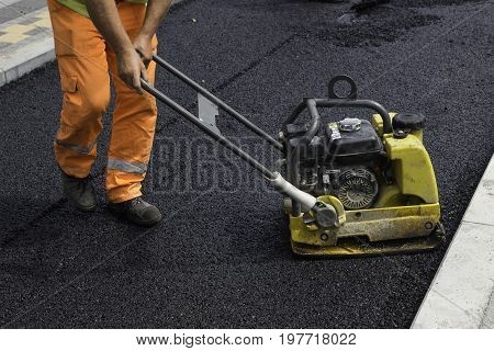 Worker With Vibrating Compactor Plate In Action