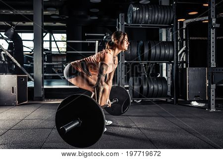 Muscular young fitness woman doing heavy deadlift exercise in gym