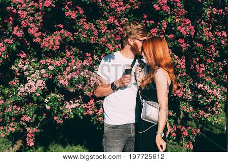 Couple in park eating ice cream cones, posing on camera