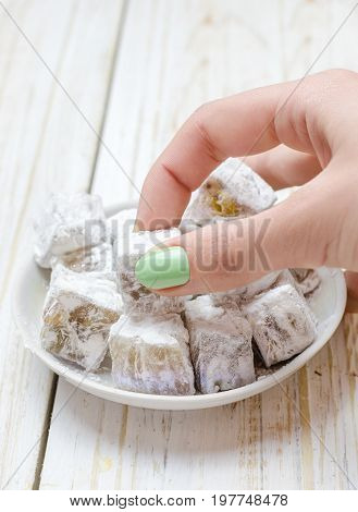 Turkish delight with pistachios on white wooden background.