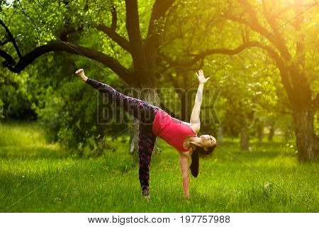 Young woman standing in half moon pose, while practicing yoga. Female doing yoga exercise ardha chandrasana. Toned image.