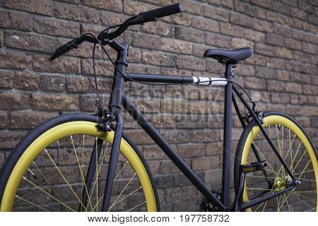 Black and gold bicycle in front of a brick wall