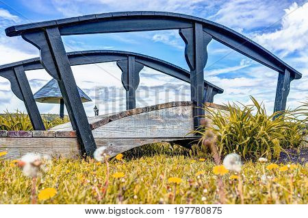 Small Bridge By Yellow Dandelion Flowers By Saint Lawrence River In La Malbaie, Quebec, Canada In Ch