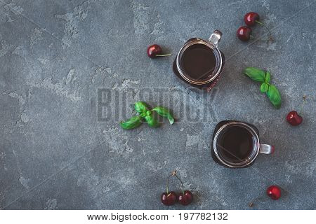 Cherry juice and fresh cherries on black background. Top view flat lay
