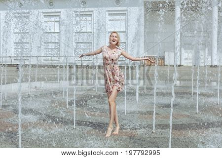 Woman is playing in a fountain she is delighted with happiness.