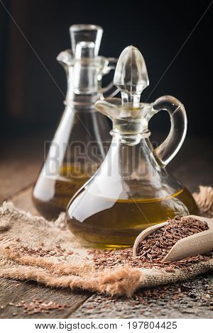 flax seeds and linseed oil in a glass jug on a wooden table, healthy diet with omega 3 fatty acids