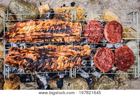 Pork Ribs And Burgers On Homemade Improvised Bbq Barbecue Grill.