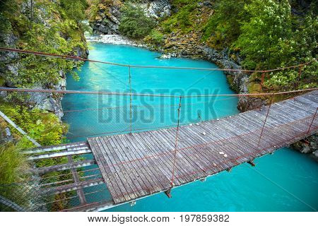 small rope bridge over green Utla river in Utladalen, Norway