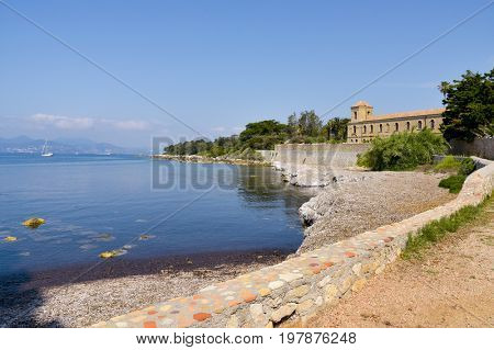 a view of the Lerins Abbey in the Saint-Honorat island, France, with the coast of Cannes in the background
