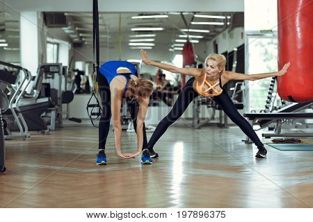 Two young athletic women train together in the gym