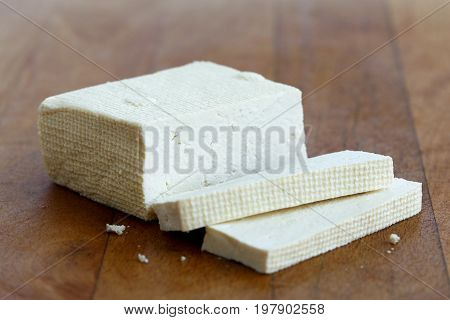 Block Of White Tofu And Two Tofu Slices On Wooden Chopping Board.