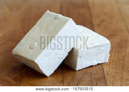 Two Blocks Of White Tofu On Wooden Chopping Board.