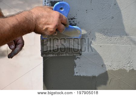 Hands Of An Old Manual Worker With Wall Plastering Tools Renovating House. Plasterer Renovating Outd