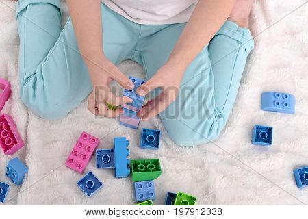 Little kid playing with toys constructor. Close up