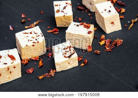 Slices of raw tofu slices of raw tofu on a black background, sprinkled with paprika.