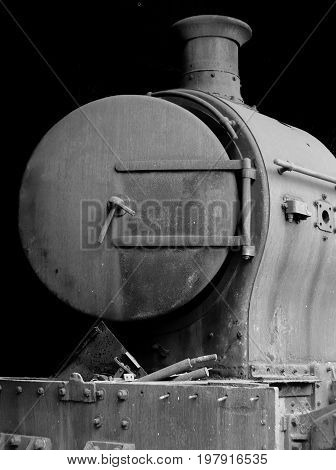 old rusty steam locomotive with door open and chimney in front view on black background