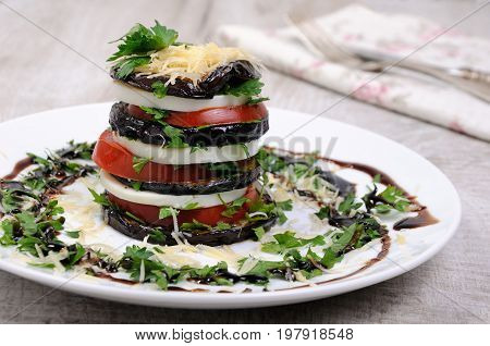 Appetizer from eggplant slices of mozzarella combined in a pile with tomatoes spilled with herbs seasoned Parmesan cheese