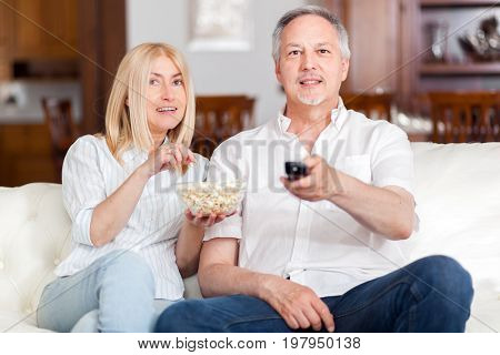 senior couple watching tv and eating pop-corn