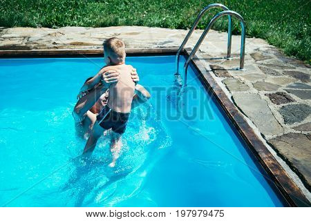 Father and his son having fun in the swimming pool on beautiful summer day.