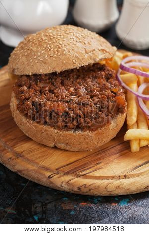 Ground beef burger sandwich with french fries on wooden board