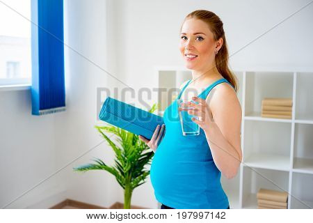 A portrait of a pregnant woman drinking water