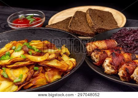 Roasted Potato In The Pot, Pieces Of Rye Black Bread On A Wooden Serving Plate, Homemade Sausages In