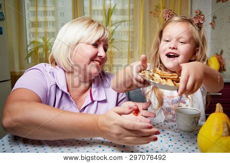 Adalt Mother And Her Young Daughter In A Kitchen With Pancakes