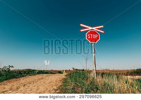 Crossbuck And Stop Sign On Countryside Road And Railway Intersection Against Blue Sky