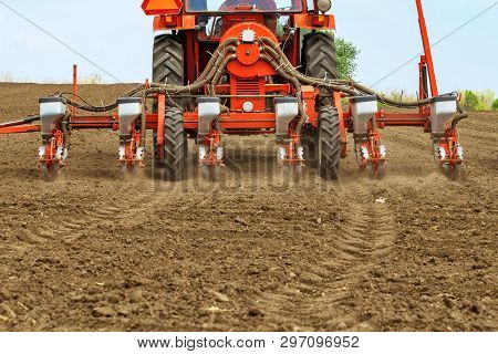 Unrecognizable Farmer Is Driving Tractor With Mounted Crop Seeder And Planting Corn Seed In Field