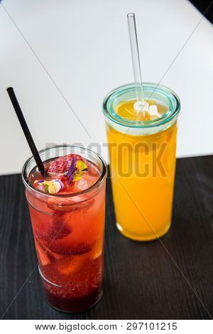 fresh lemonade with  straws with fresh strawberry and orange on a bar table