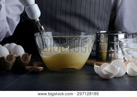 Dough Pouring From The Whisk. Man Manking Pie. Recipe Concept On Dark Background