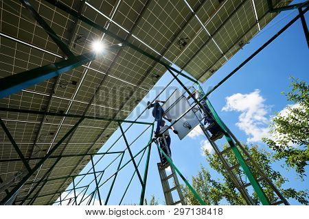 Three Mounters Holding Solar Panels On High Metallic Construction. Work, Needing Special Equipment. 