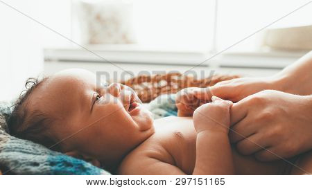 Newborn Baby Smiling At Mother. Happy Motherhood. Mom Holding Cute Little Child Hands With Love And 