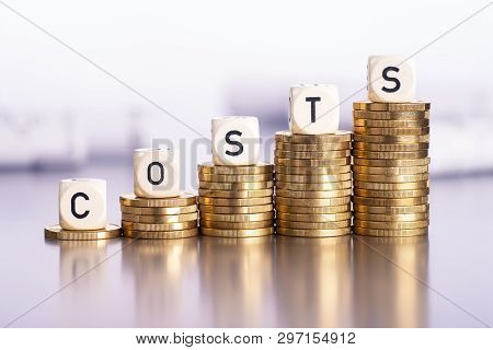 Rising Stacks Of Coins With The Word Costs