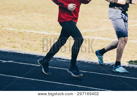 Two Running Man Training Outdoors On A Rubber Track. Runner At The Stadium On A Sunny Day. Cropped S