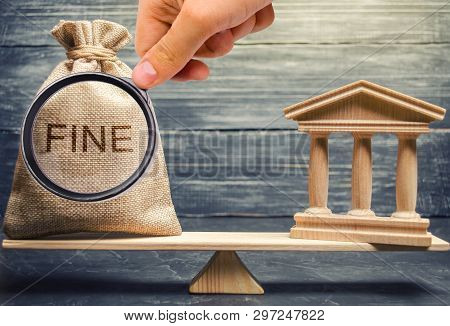 Money Bag With The Word Fine And The Courthouse Or Bank On The Scales Of Justice. The Concept Of Pay